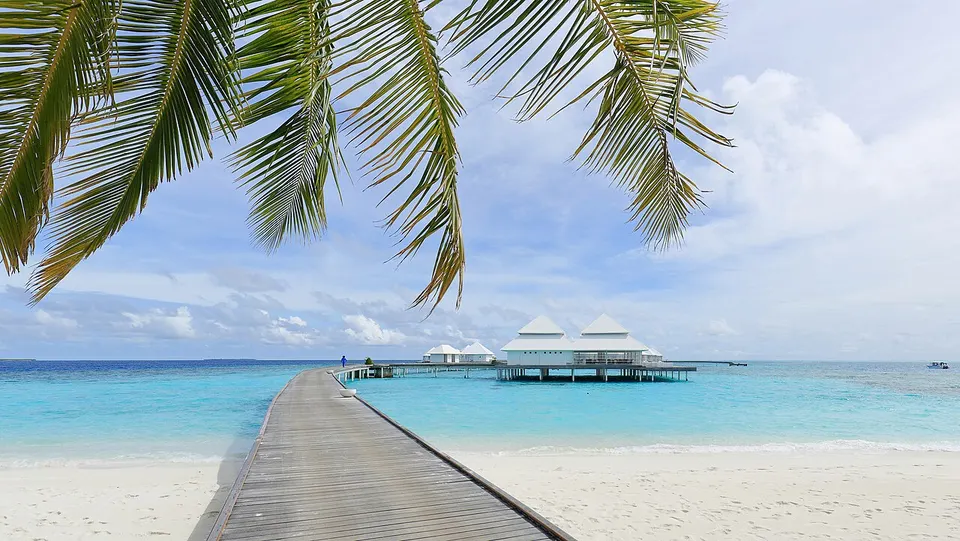 Weißer Sandstrand und Wasservillen auf Stelzen über der türkisfarbenen Lagune der Insel Thudufushi auf den Malediven