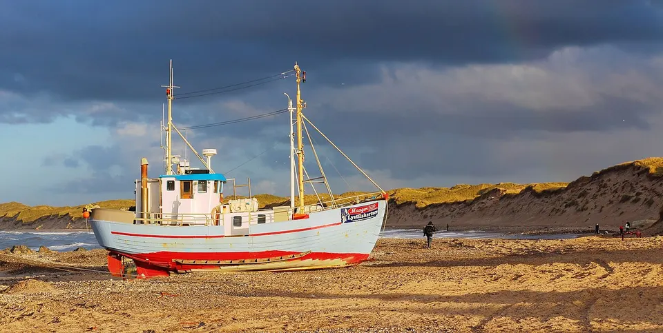 Nordjütland: The leisure fishing boat Maagen on the beach of Nørre Vorupør, Denmark. Can you see the rainbow?