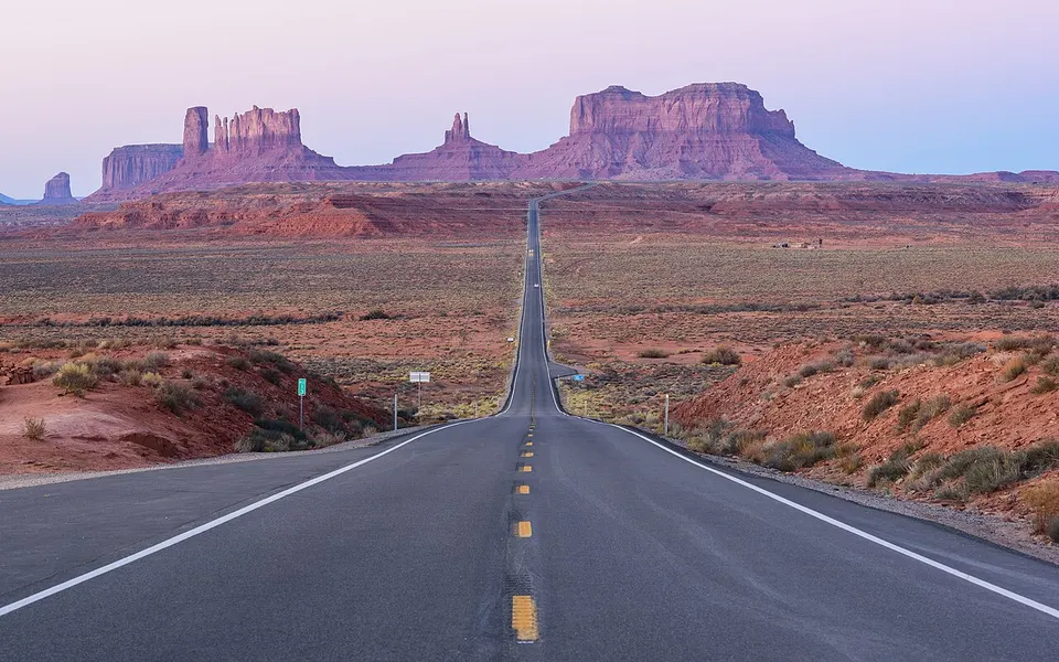 Gerade Straße, die auf die roten Tafelberge des Monument Valley zuführt