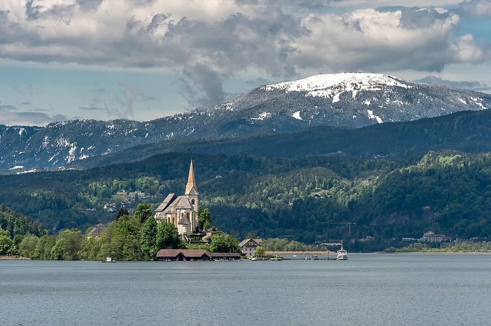 Die Pfarrkirche von Maria Wörth auf ihrer Halbinsel im Wörthersee, dahinter der Berg Gerlitzen