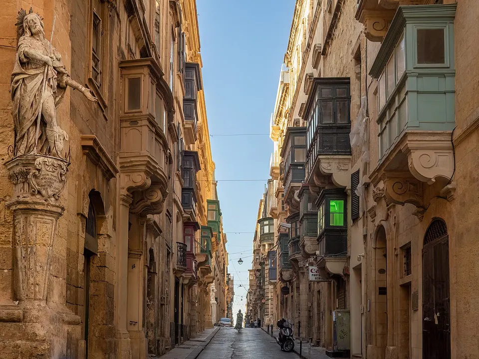 Steile Gasse Saint Christopher Street in Valletta mit Sandsteinhäusern und bunten Holzbalkonen