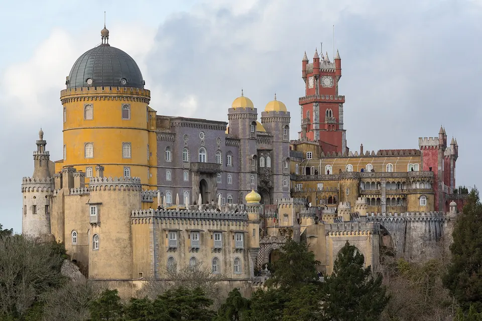 Der bunte Pena-Palast in Sintra mit gelben und roten Türmen auf einem bewaldeten Hügel